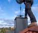 chimney-sweep-cleaning-a-chimney-standing-on-the-house-roof-lowering-picture-id1284524676